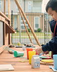 School child playing at a timber mud kitchen in a school yard