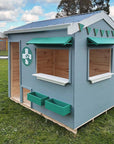 A vet themed grey and green cubby house on grass in a school yard close up