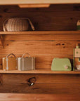 A wooden Shelf with trinkets and toys on it, inside a wooden cubby house.