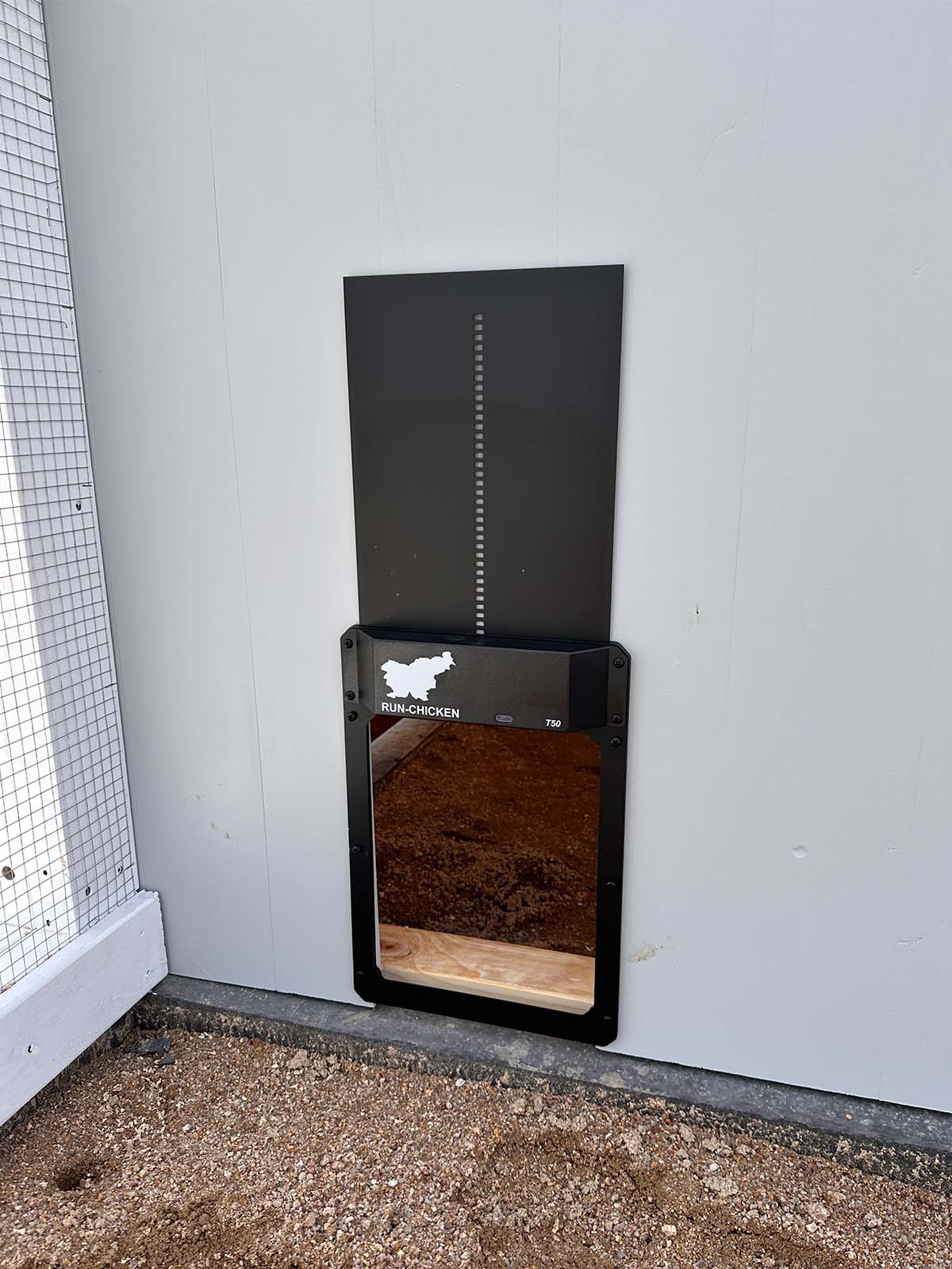 Close up of automated chicken door on Grey chicken coop wall