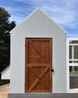 Close up of a thermory timber door on a large grey barn style chicken coop on a sunny day