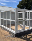 White timber chicken run and gate attached to a large barn style chicken coop on a sunny day