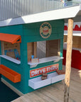A green painted wooden burger shop cubby house in a school playground