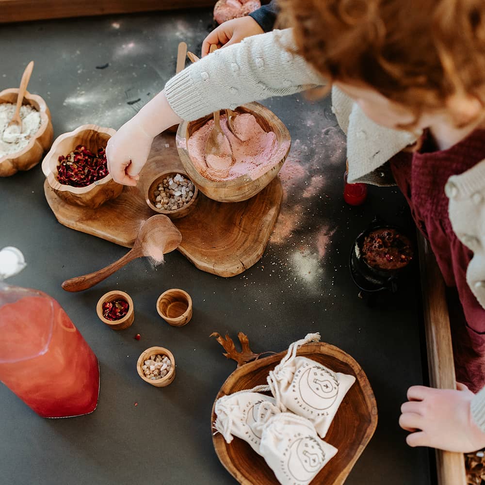 Close-up of Exploration & Loose Parts Table in an ELC, with children using coloured sand and sensory play materials on the chalkboard top.