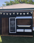 A painted farmers market themed wooden cubby house in an education setting