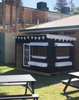 A painted farmers market themed wooden cubby house in a early learning centre play space