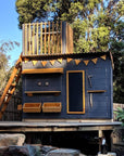 A charcoal painted wooden cubby house with fort top and ladder