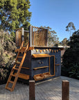 A painted wooden fort top cubby perched on a deck in a beautiful garden
