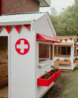 A painted wooden hospital themed cubby house with red cross sign