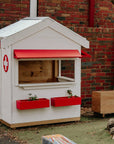 A school grounds with white and red hospital style timber cubby house