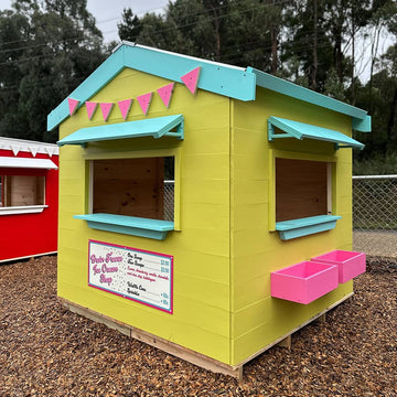 A bright yellow aqua and pink ice cream shop cubby house in a school playground