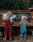 Two girls playing barefoot at an outdoor timber mud kitchen
