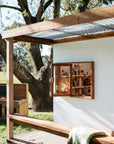 Angled view of cubby house showing timber window and bench seat under corrugated roof