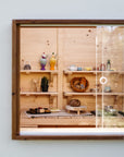 Close-up of toy kitchen through perspex window of cubby house with timber detailing
