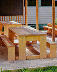 Timber outdoor table and bench seat set in a school garden with raised garden bed and shade structure