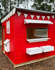 A red and white painted wooden cubby house styled as a post office in an education village play space