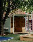 An aqua painted potting shed in front of a garden bed in a school playground