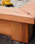 Corner detail of timber raised sandpit with toy truck in the background