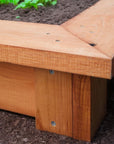 Close-up of a wooden raised garden bed with soil in the background