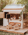 A child plays inside a beautiful white and timber pitched roof cubby house