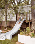 A woman waits to catch her child at the end of a white slide