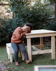 A smiling girl sitting at a pine wooden kids table