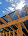 Timber pergola detail with a blue sky and sun in the background