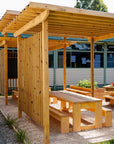 Timber picnic table with benches under a Timber pergola in an outdoor setting.
