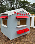 A grey and white painted wooden vet cubby house as part of a school cubby village