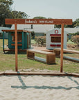 A welcome sign in a school setting in front of village themed cubby houses