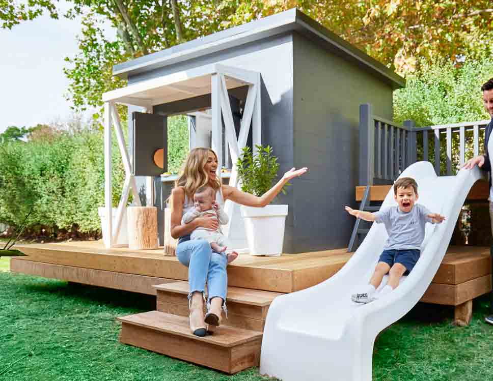 A cubby house with a wooden decking and a slide
