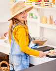 A girl plays at her colourful cubby house kitchen bench