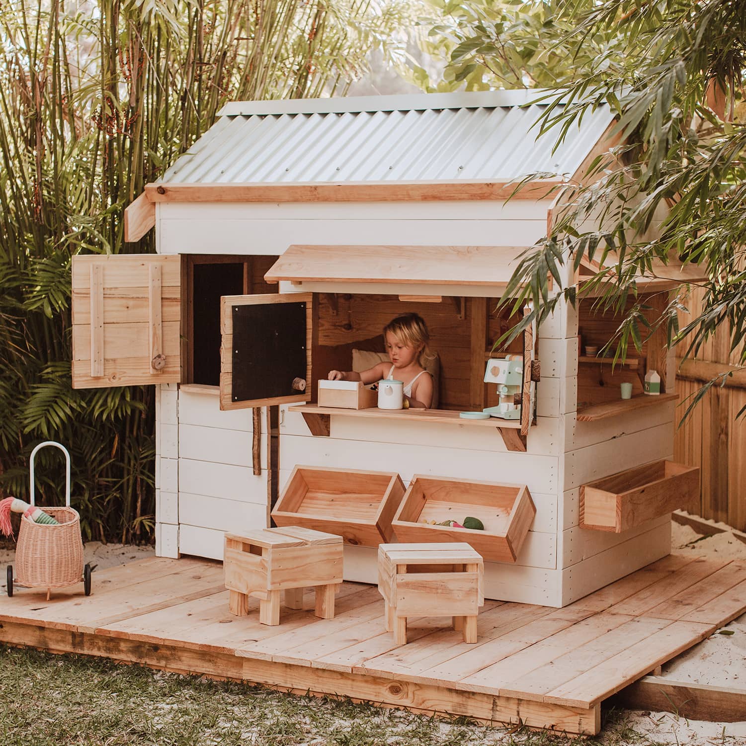 A white painted wooden cubby house on decking panels