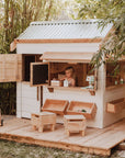A white painted wooden cubby house on decking panels