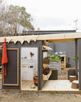 A painted wooden cubby house with front verandah in a childcare education outdoor space.