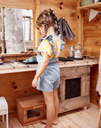 A girl plays at her cubby house kitchen bench