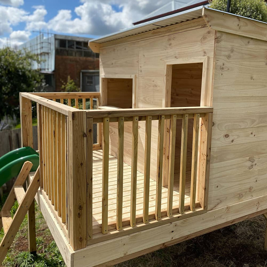 A close up of a timber handrail surrounding a cubby house on raised decking