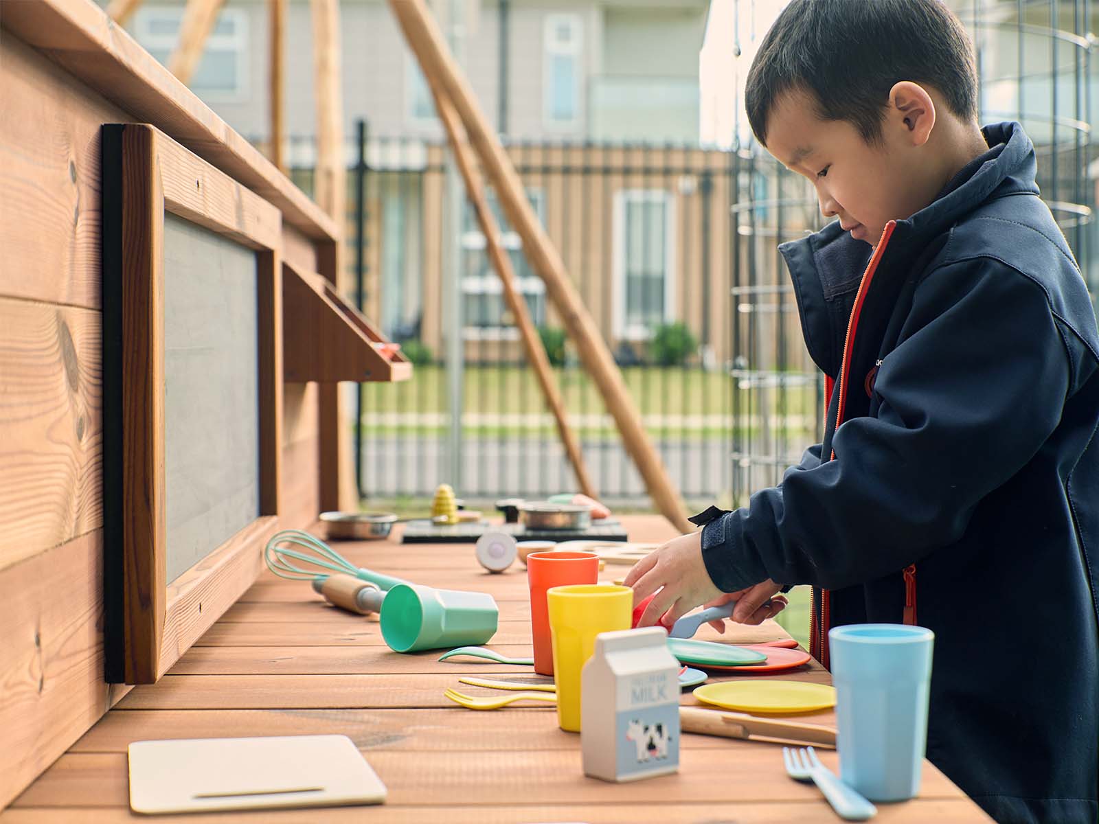 School child playing at a timber mud kitchen in a school yard