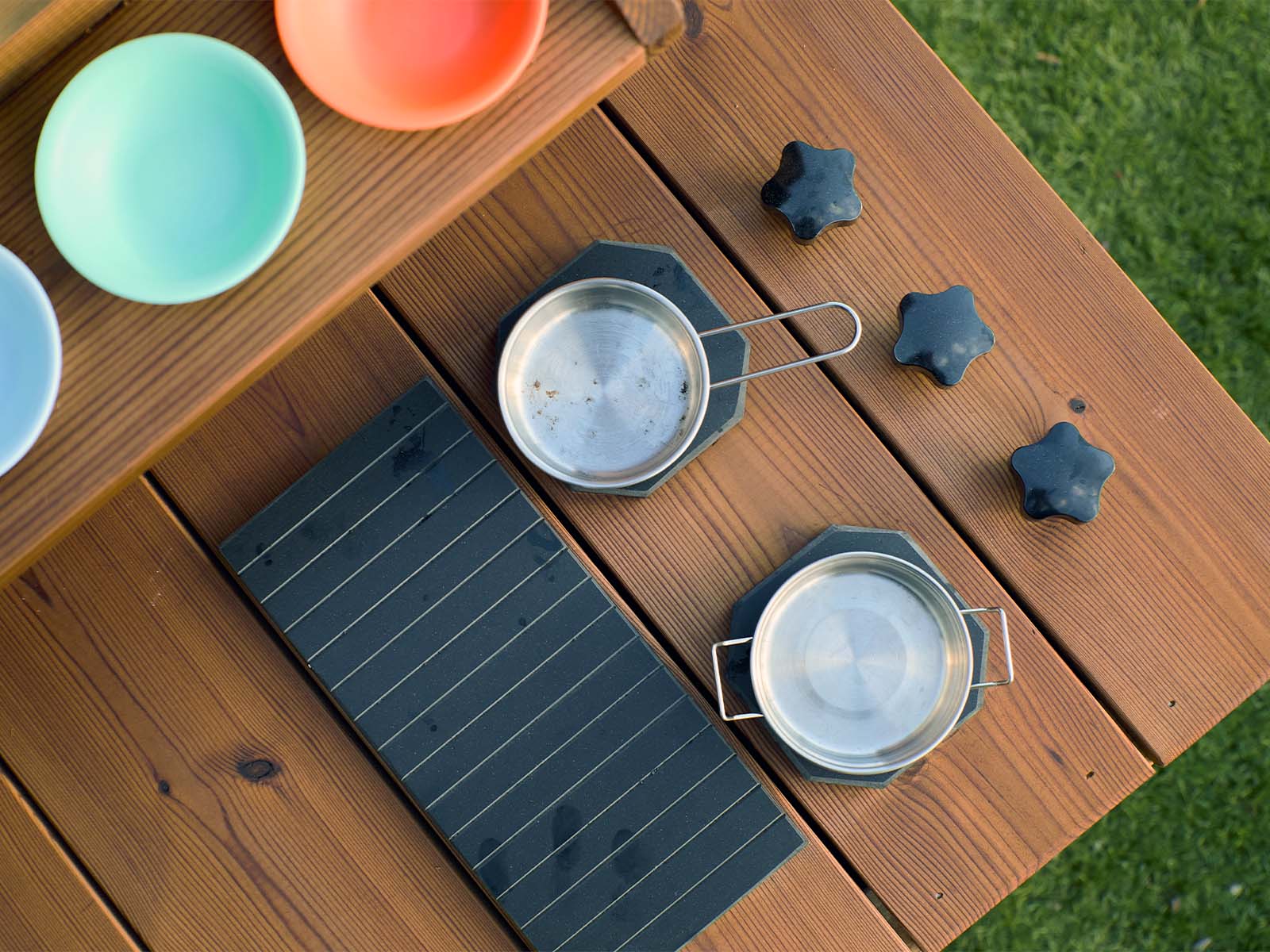 Detail vertical image of a play hot plate, grille and knobs on a timber mud kitchen on grass with two pots 