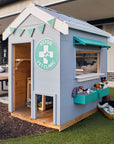 A vet themed grey and green cubby house in a school yard staged with soft toys 