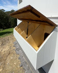 Detail shot of an open plywood and thermory timber 4 way nesting box with gas strut lid on side of chicken coop
