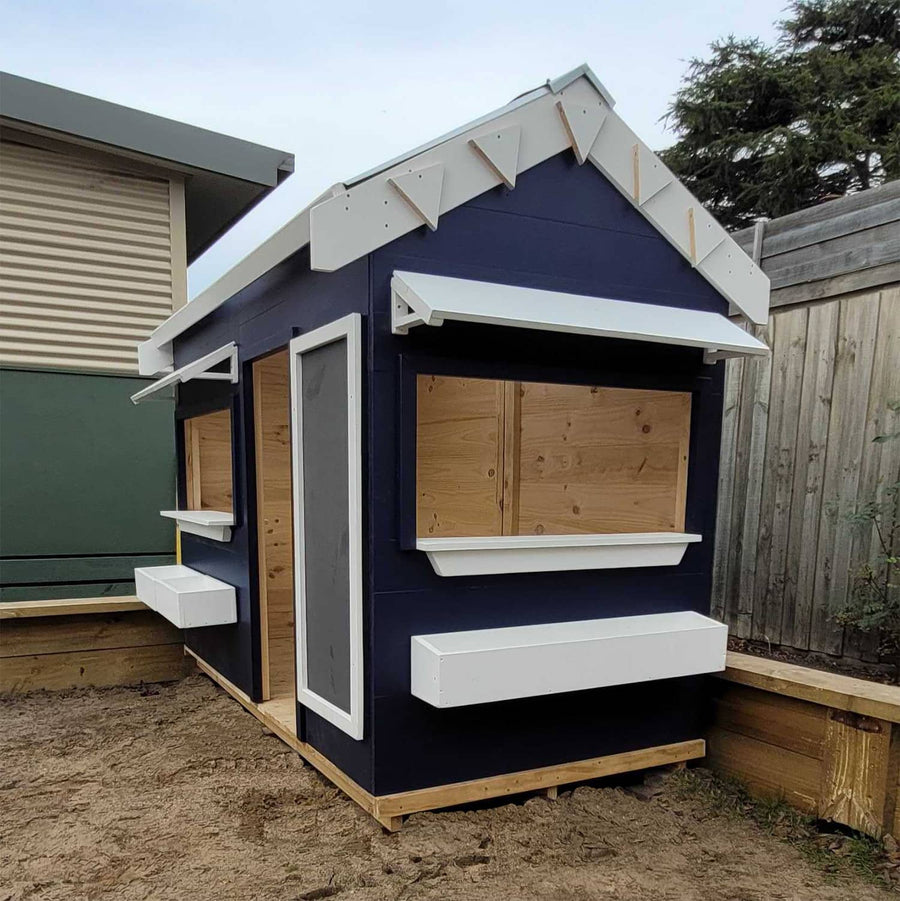 A commercial grade pitched roof cubby house painted navy blue with white trims