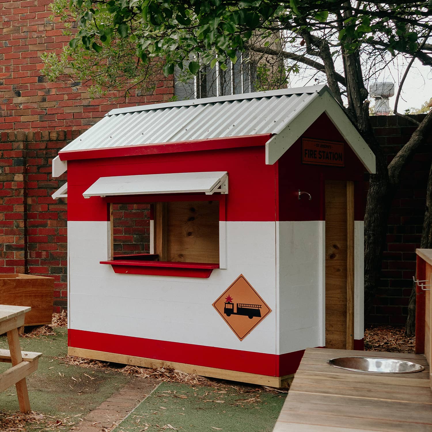 A painted fire station wooden cubby house in a school playground