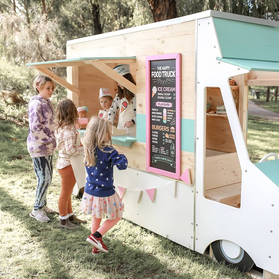 Kids serving at a foodtruck themed cubby house in a playground