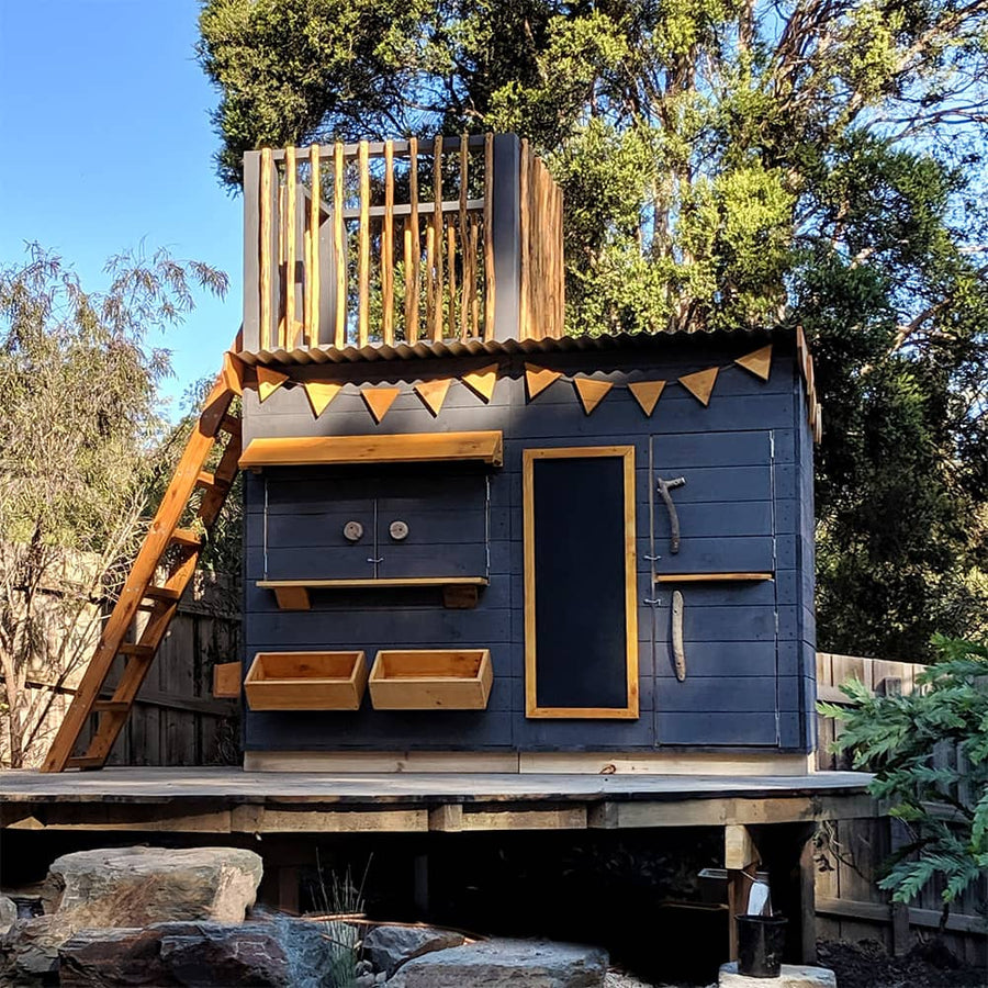 A charcoal painted wooden cubby house with fort top and ladder