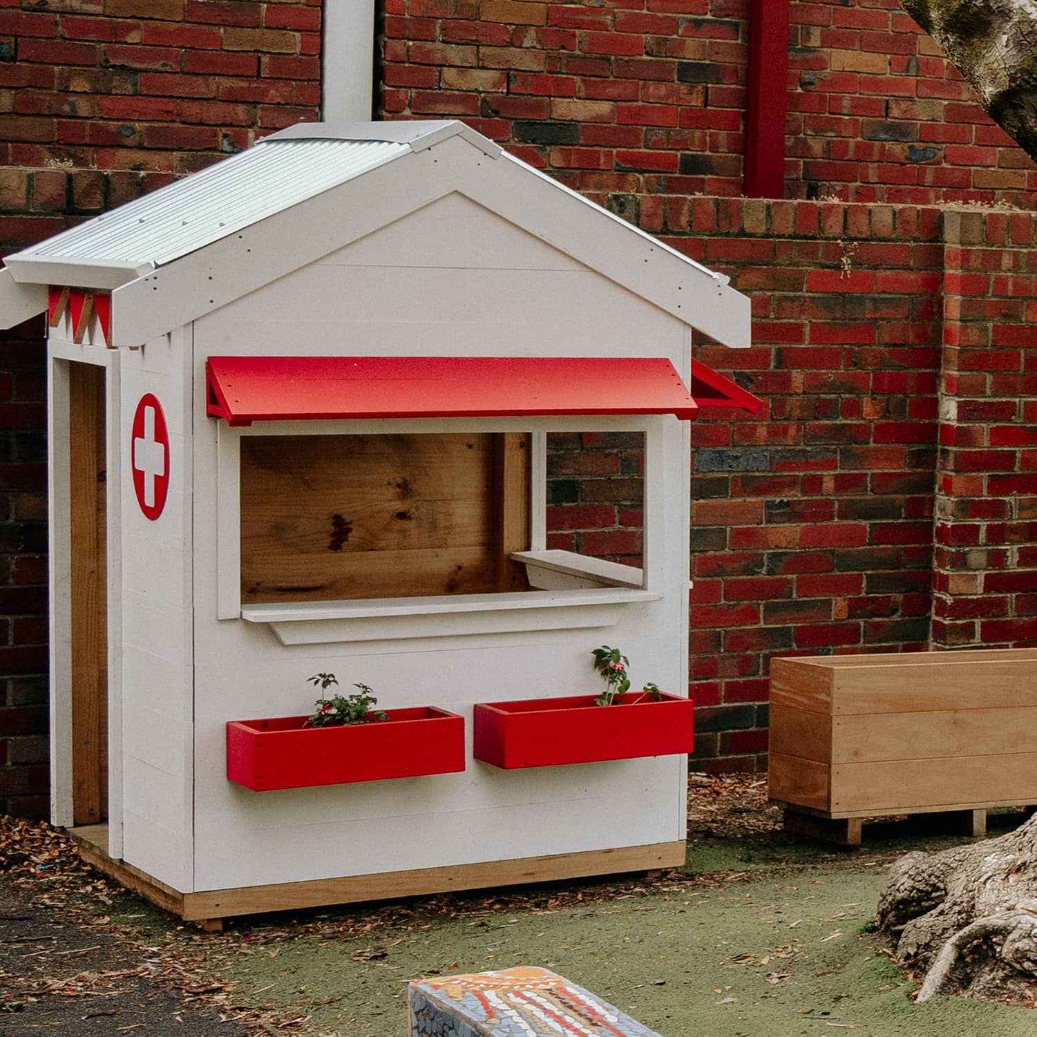 A school grounds with white and red hospital style timber cubby house