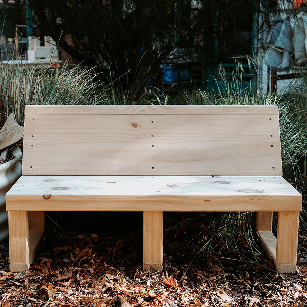 A pine timber bench seat with sloped back in an early learning centre yard
