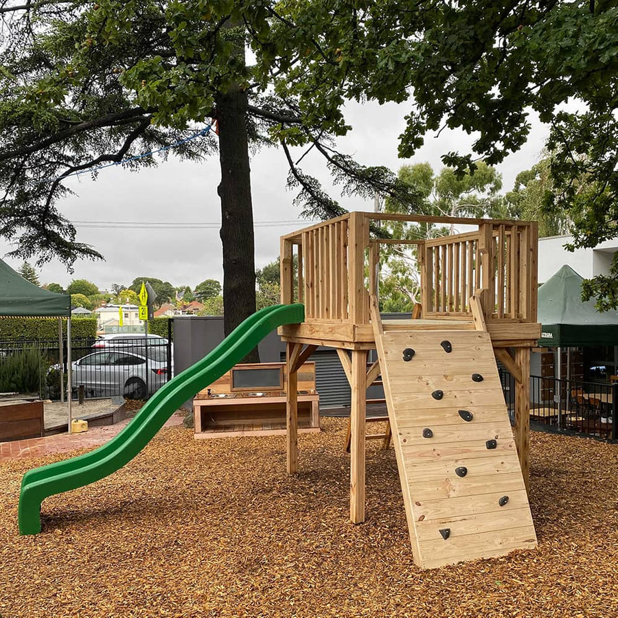 A beautiful timber platform in a nature play space with climbing wall and slide
