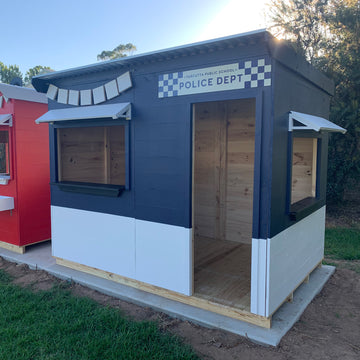 A navy and white painted wooden cubby house styled as a police station in a school play ground