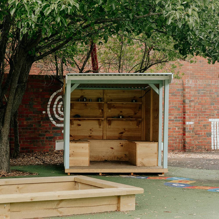 A painted wooden potting shed with storage boxes in a school playground